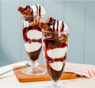 Two Table Table sundaes in glasses with red cherry sauce and chocolate drizzle.